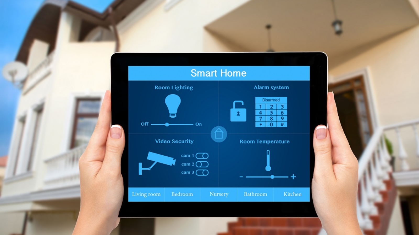 Female hands hold a tablet computer with system smart house on a screen on the background of the house